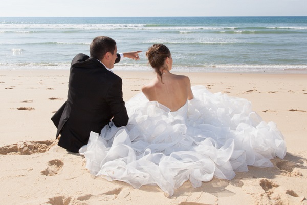 Bride and groom sitting on the beach